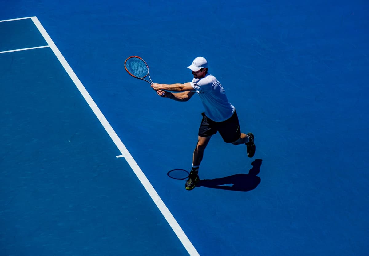 Man plays tennis on a blue court