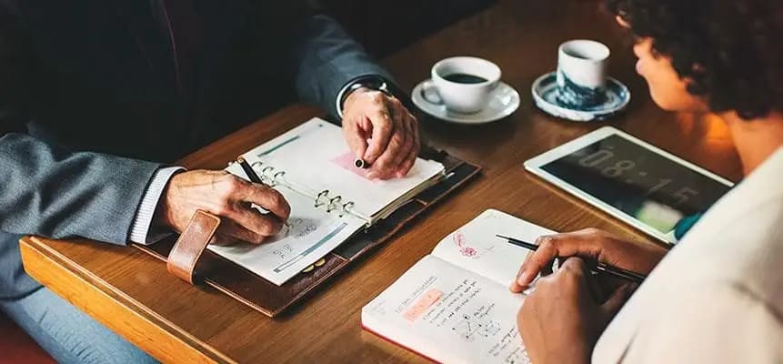 People take notes at a table in a coffee shop