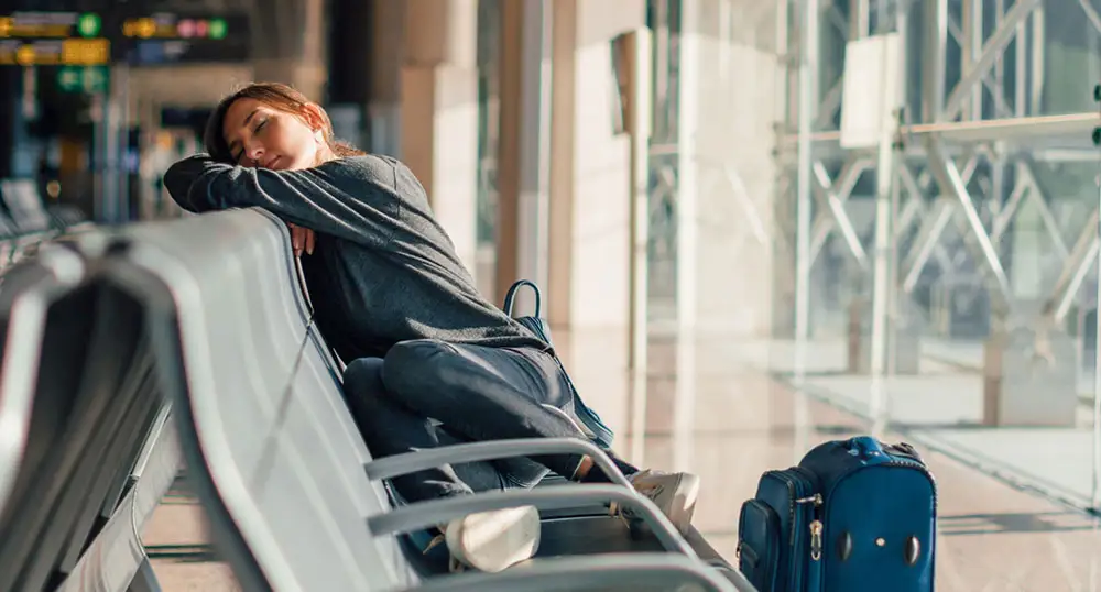 Woman sleeping uncomfortably in the seats at the airport terminal