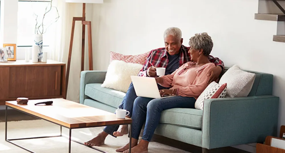 Couple sits on a couch, using a laptop