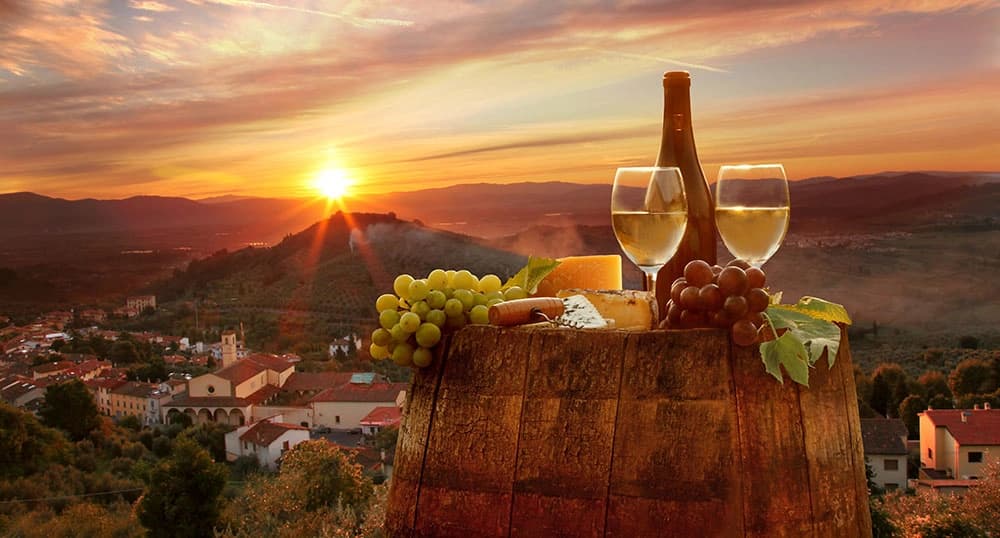 Food and Wine sit on top of a cask with a sunset-dappled mountain in the background