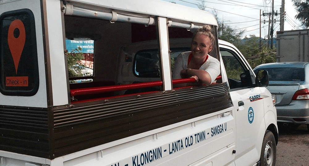 Smiling woman leans out of a bus window.