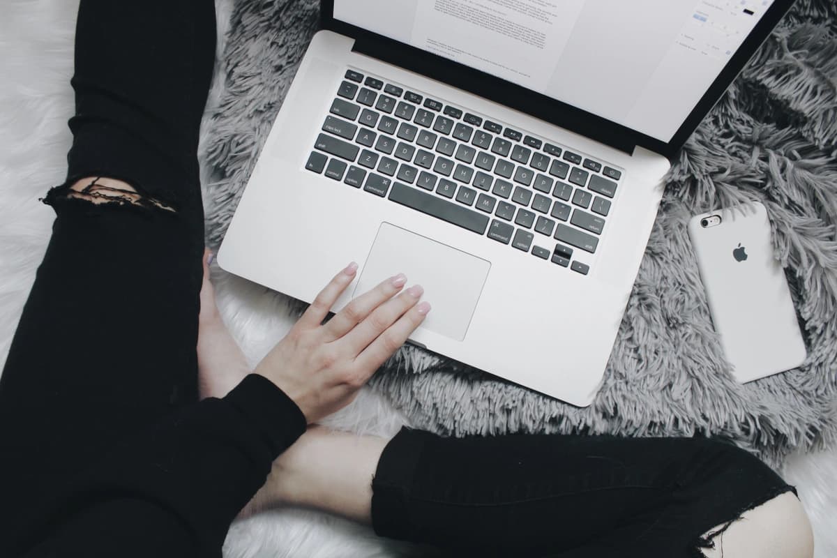 Person sits on the floor, typing on laptop