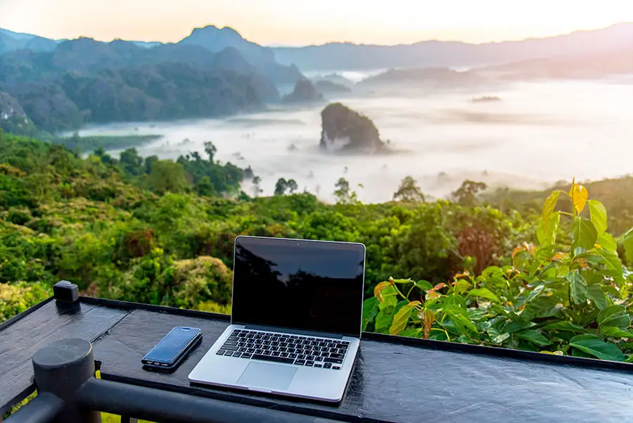 Laptop sits on a counter overlooking tropical coastline