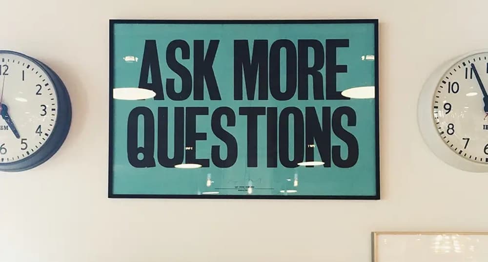 Sign on the wall reading "Ask more questions"