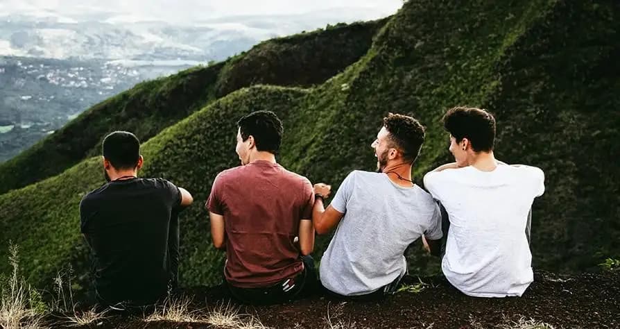 Five young me sit on a ledge in the mountains